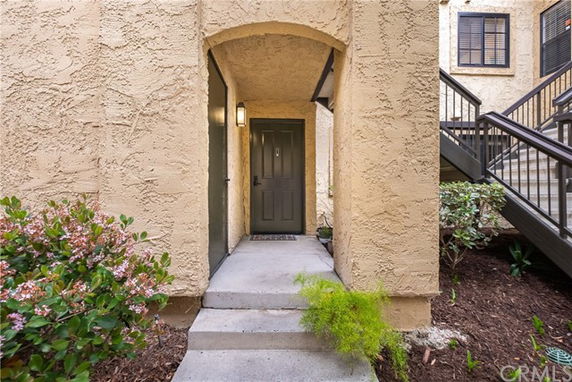 Entrance of a building with an arched entryway and stairs leading to a dark door.