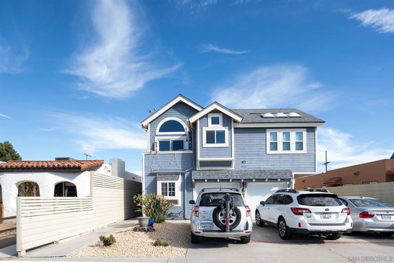 Front view of a two-story house with a double garage and multiple cars parked in the driveway.