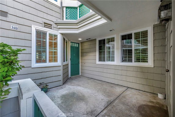 Front view of a house entrance with green door and windows with shutters.