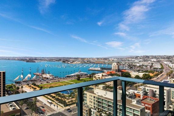 Panoramic view from a high point showcasing a waterfront with boats and a cityscape under a clear blue sky.