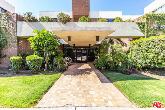 Front view of a multi-story building with an entrance canopy and surrounding greenery.