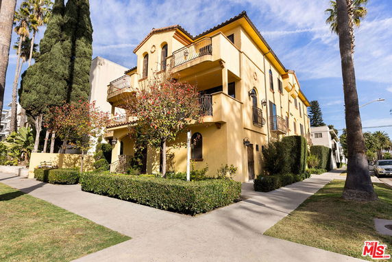 Front view of a multi-story house with balconies and a yellow exterior.