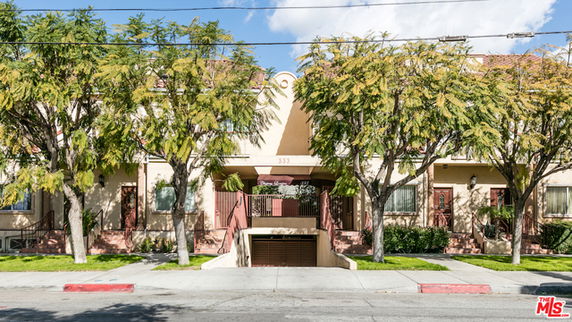 Front view of a multi-story residential building with an entrance and landscaped area.