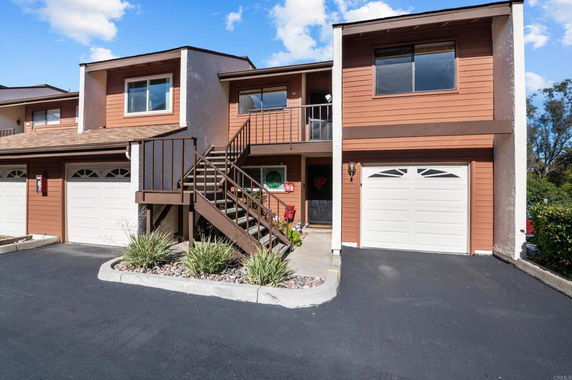Front view of a two-story townhome with garage and outdoor stairway.