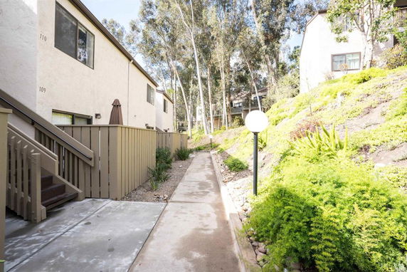 Side view of apartment buildings with walkway and greenery.