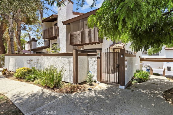 Front view of a multi-story house with wooden balconies and gated entrance.