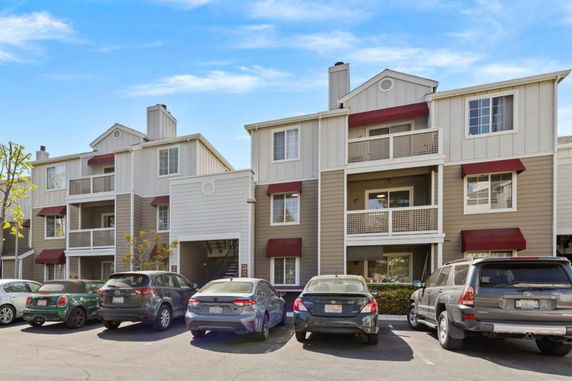 Front view of a multi-story apartment building with balconies and parking area.