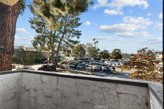 View from a balcony showing a parking area and trees.