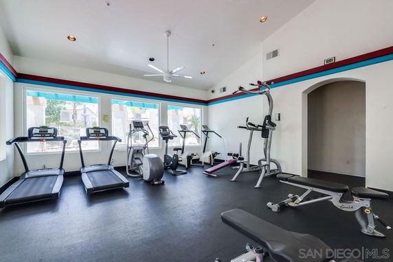 Indoor gym area with exercise equipment and large windows.