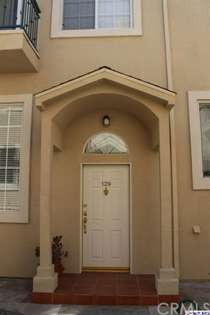 Front view of a house entrance with an arched porch and windows.