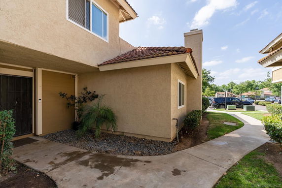 Exterior view of a house with beige stucco walls and a tiled roof.