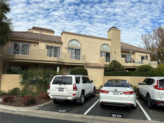 Front view of a two-story building with balconies and a tiled roof.