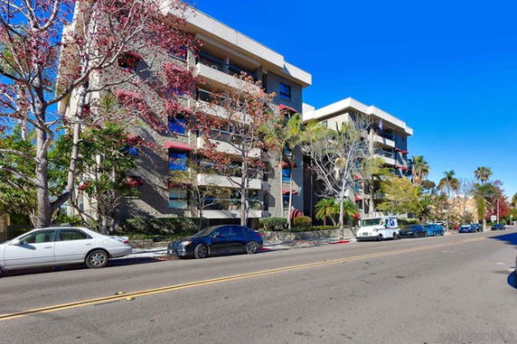 Front view of a multi-story building with balconies and adjacent street.