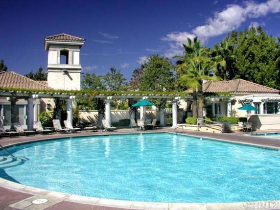 Outdoor swimming pool area with surrounding lounge chairs and umbrellas.