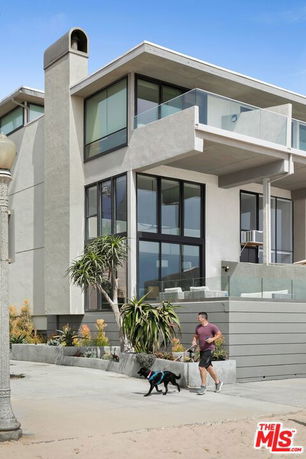 Front view of a modern multi-story house with large glass windows and a chimney.