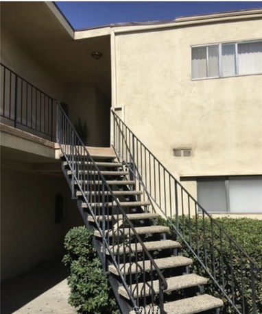 Staircase leading to the upper level of a beige-colored building exterior.