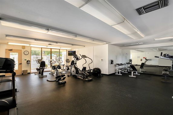 Indoor gym area with exercise equipment and large mirrors.