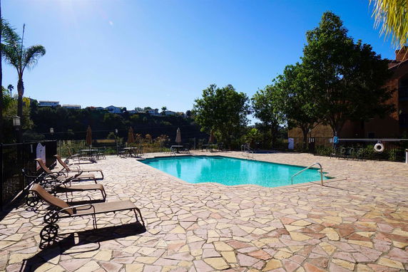 Outdoor swimming pool with lounge chairs and surrounding trees.