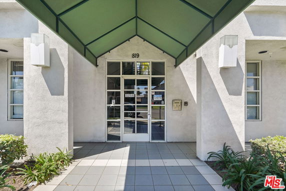 Front view of a building entrance with a glass door and green awning.
