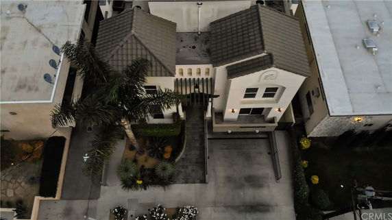 Aerial view of a two-story house with a tiled roof and driveway.