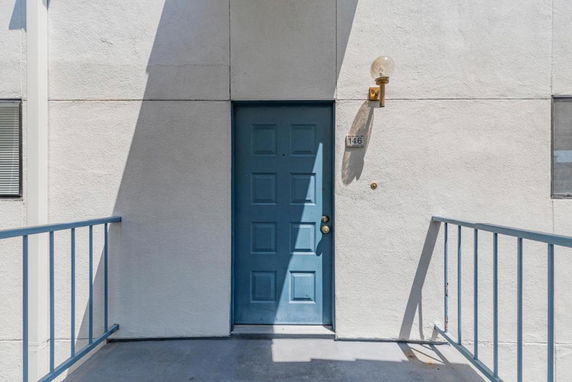 Front view of a building entrance with a blue door and metal railings.