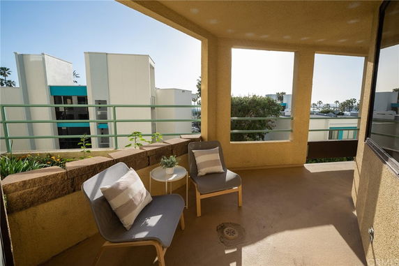 View from a balcony overlooking nearby buildings with ocean in the distance.