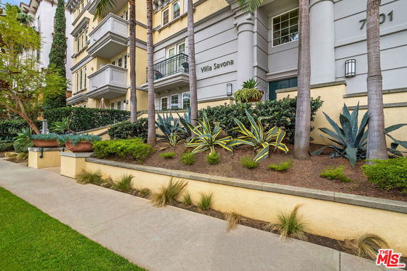 Front view of a multi-story building with balconies and landscaped garden.