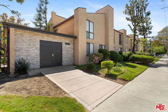 Front view of a multi-story building with a modern facade and a small driveway.