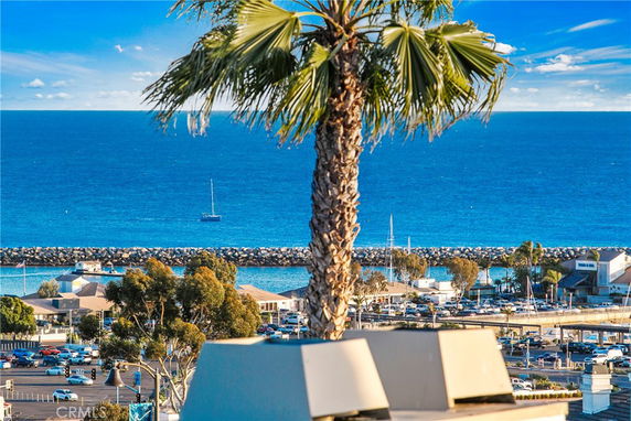 Panoramic view of the ocean with sailboats and a nearby marina, as seen from a rooftop.