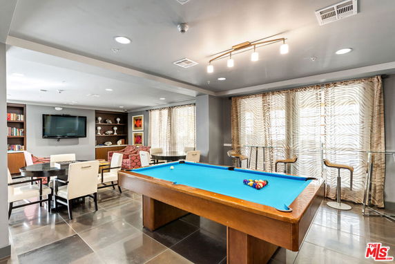 Interior view of a recreational room with a pool table and seating areas.