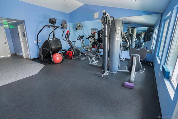 Indoor gym area with exercise equipment and mirrors on the wall.