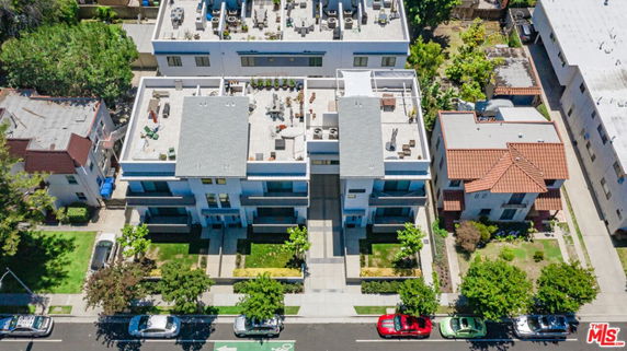 Aerial view of modern residential buildings with well-structured rooftops, featuring seating areas and greenery.