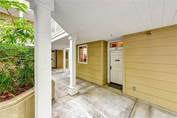 Front view of a building entrance with a covered walkway and beige siding.