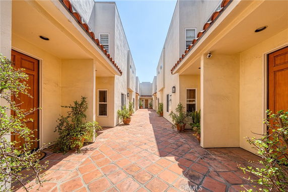 Outdoor view of a pathway between two buildings with doors and small windows.