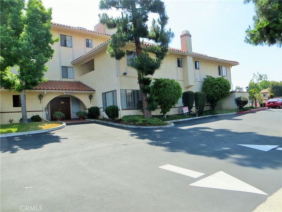 Front view of a multi-story building with a tile roof and landscaped entrance.