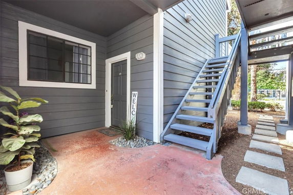 Front entrance area of a building with an external staircase and a door.