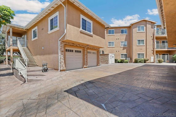 Front view of a multi-story residential building with garages and stairs.
