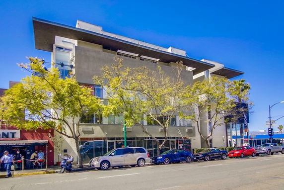 Front view of a modern multi-story building with large windows and a flat roof.