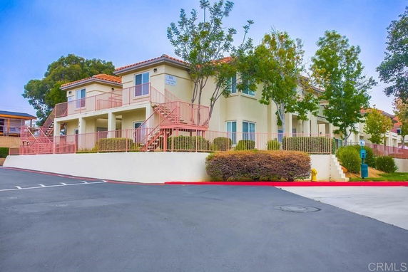 Front view of a multi-story residential building with outdoor staircases and railings.