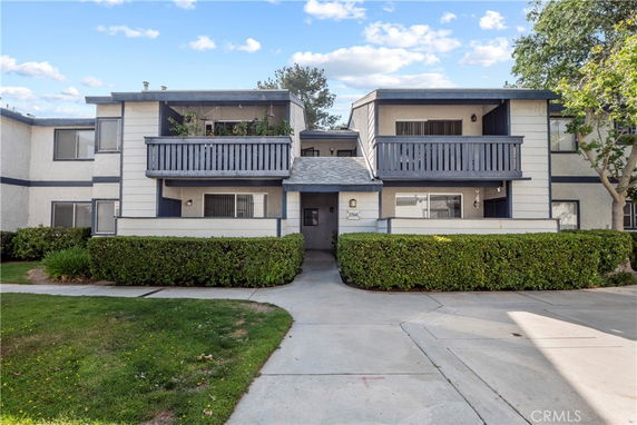 Front view of a two-story house with balconies and shrub landscaping.