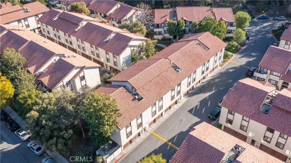 Aerial view of residential buildings with red-tiled rooftops and surrounding streets.