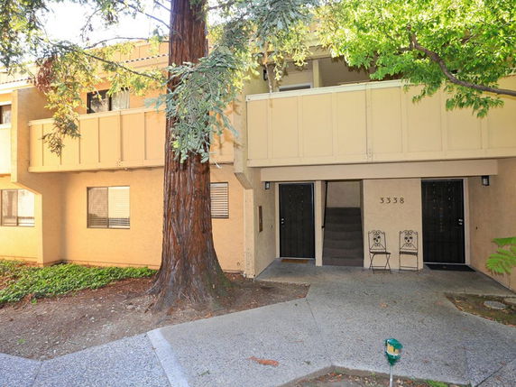 Front view of a two-story residential building with a small balcony and two entrance doors.