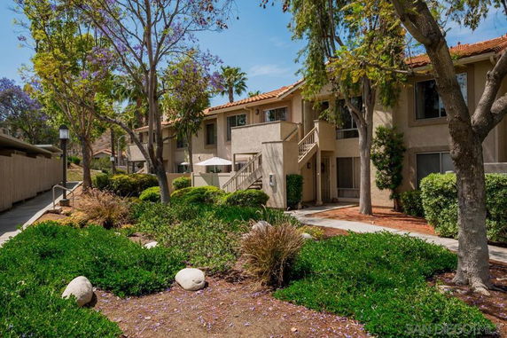 Front view of a two-story residential building with trees and shrubs.