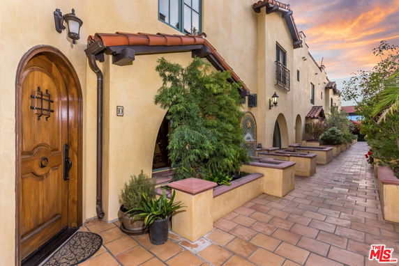 Front view of a row of houses with arched doorways and decorative planters.