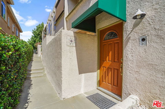 Side entrance of a building with a brown door and green awning.