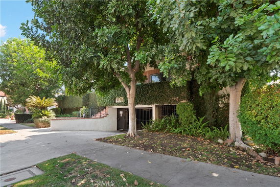 Front view of a house partially covered by trees and greenery.
