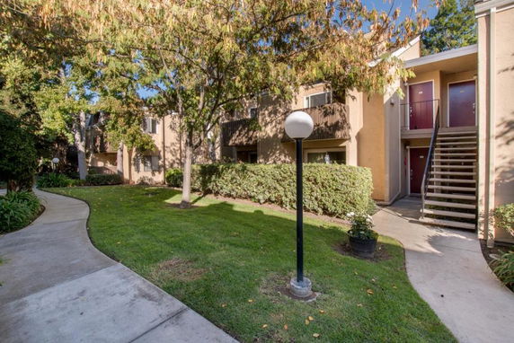 Front view of a multi-story residential building with exterior staircases and a well-maintained garden.