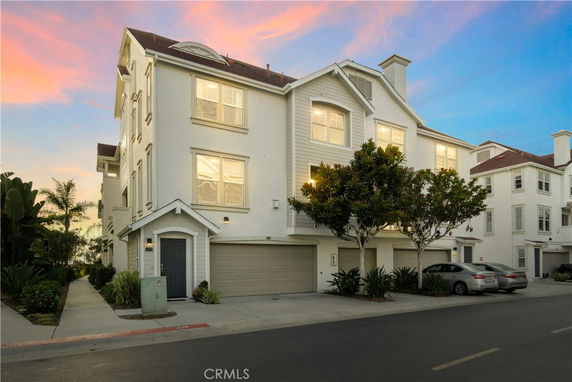 Front view of a multi-story residential building with a garage and windows.