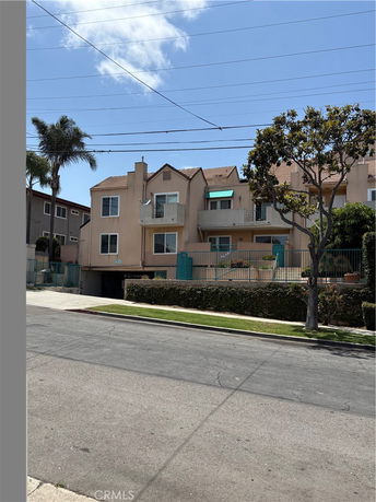 Front view of a multi-story residential building with balconies and gated entrance.
