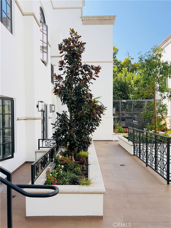 View of a white building with modern architecture and a landscaped area in front.